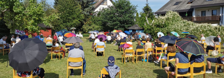 Personen mit Regenschirmen auf einer Wiese