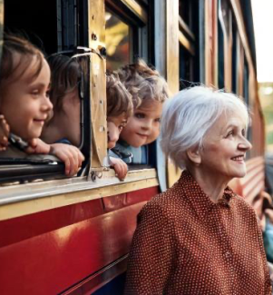 Viele Kinder Schauen aus dem Zugfenster auf dem Bahnsteig steht eine ältere Frau 
