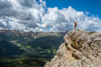 Person mit ausgestreckten Armen auf einem Berggipfel