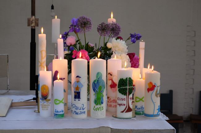 Auf dem Altar stehen viele brennende Taufkerzen.